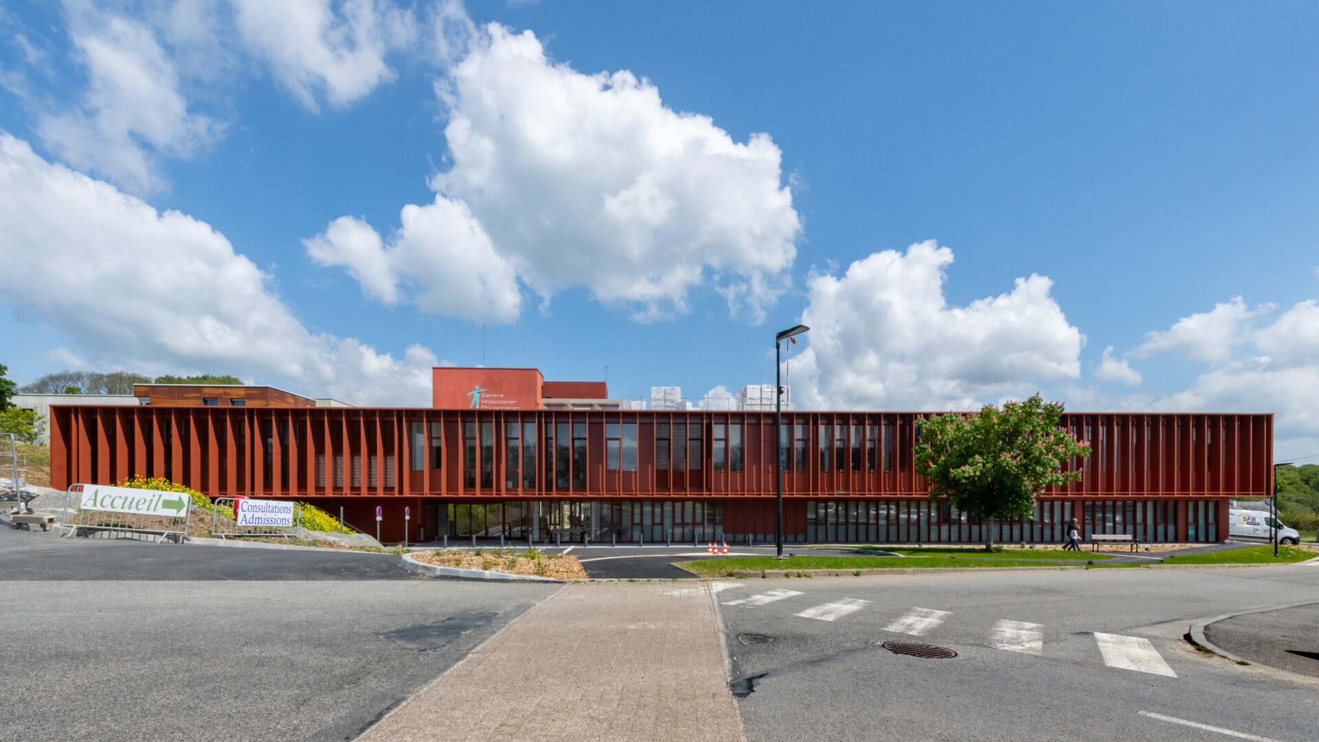 Architecture contemporaine du Centre Hospitalier de Douarnenez avec façade en lattes rouges, illustrant l'approche d'A26 en conception hospitalière innovante et intégration harmonieuse dans l'environnement