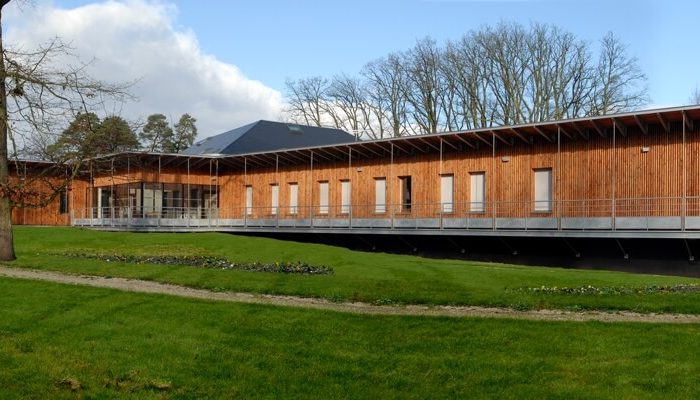 Architecture contemporaine de l'Unité de Soins Psychothérapeutiques de Fleury-les-Aubrais par A26, illustrant l'optimisation des espaces de soins et l'ergonomie hospitalière, avec un chemin accessible aux personnes à mobilité réduite.