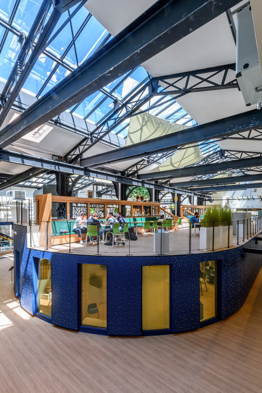 Intérieur innovant et moderne d'un espace de coworking de l'agence A26, illustrant la réversibilité architecturale avec des structures en acier et des zones de travail flexibles éclairées naturellement, promouvant une architecture mixte et un urbanisme résilient