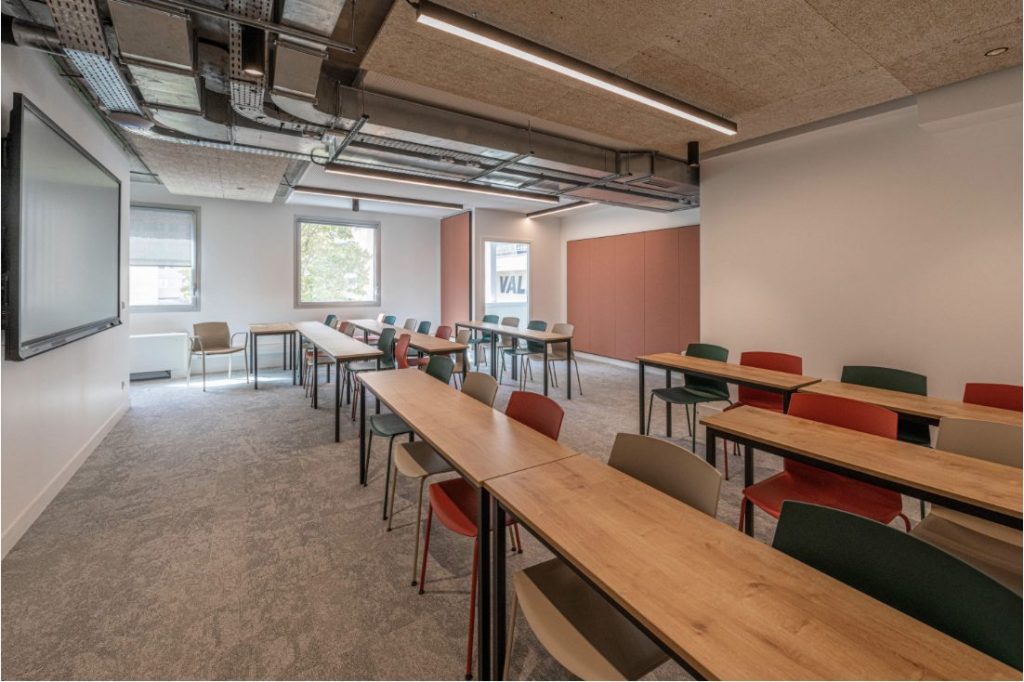 Salle de réunion contemporaine imaginée par A26 Architectures, illustrant la transformation de l'espace de bureau avec un design supportant le changement de destination d'usage, équipée pour le travail collaboratif et individuel.