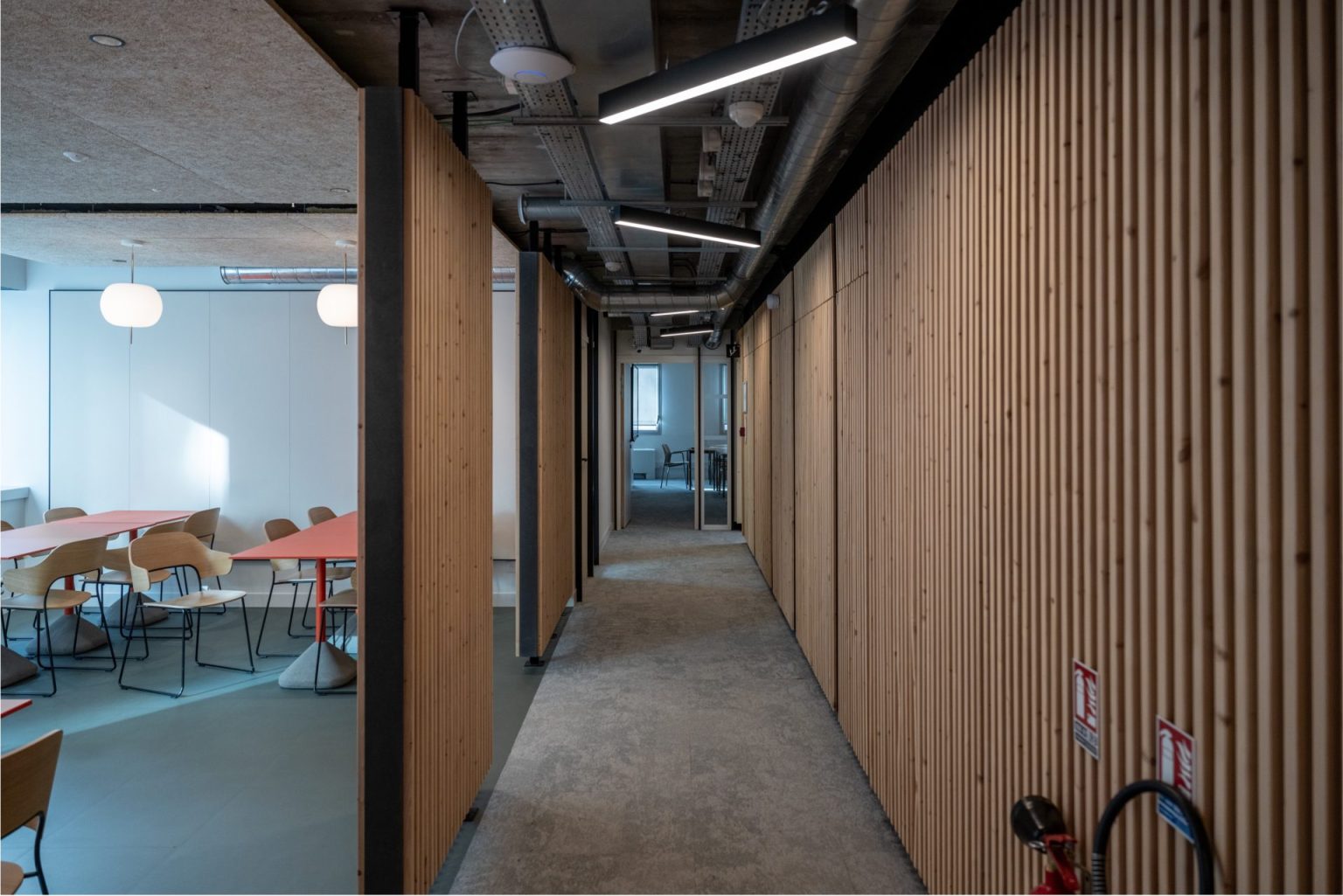 Exemple de réversibilité architecturale par A26 Architectures dans un couloir polyvalent, démontrant la transformation du bureau en espaces polyvalents et la flexibilité de changement de destination d'usage.