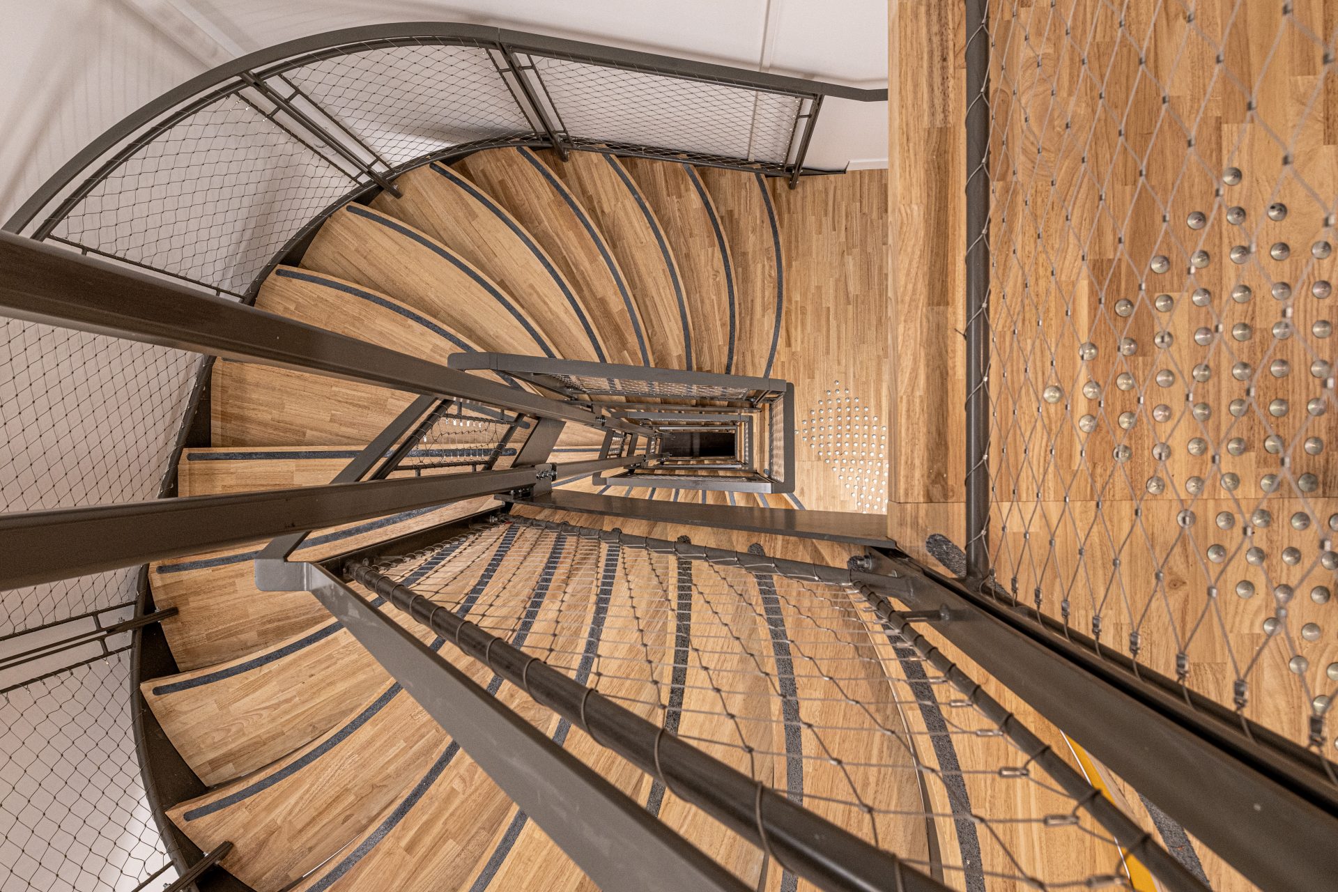 Vue en plongée sur l'escalier en colimaçon, montrant l'expertise d'A26 en conception d'espaces intérieurs réversibles