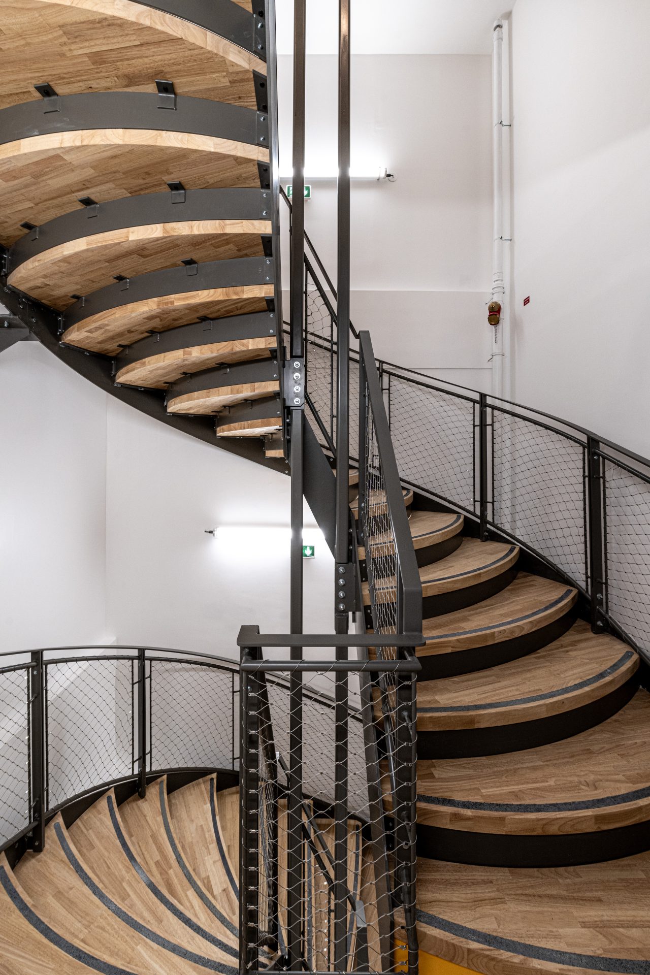 Escalier en colimaçon en bois et métal comme élément central de l'architecture intérieure, soulignant la créativité et la fonctionnalité chez A26
