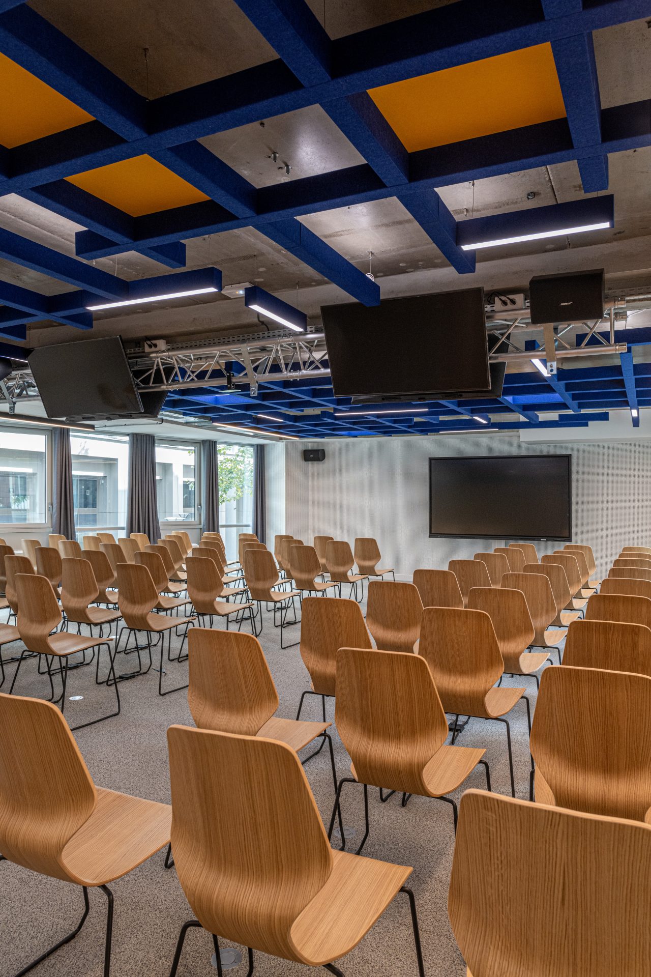 Salle de conférence contemporaine avec des sièges en bois et un design acoustique avancé, reflétant la transformation innovante d'A26