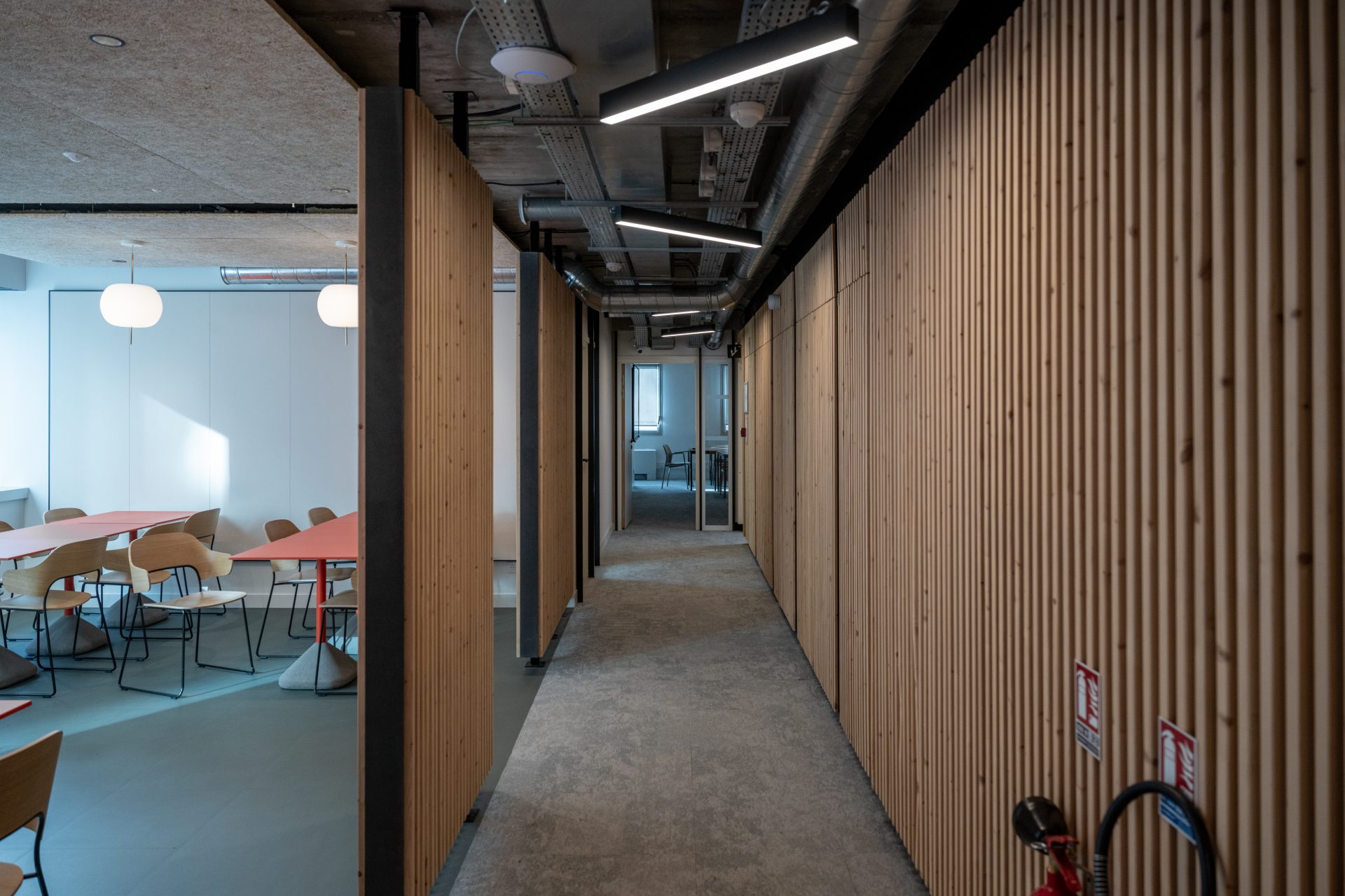 Intérieur d'un campus éducatif avec un couloir spacieux bordé de bois, illustrant l'expertise d'A26 en matière de réhabilitation de bureau